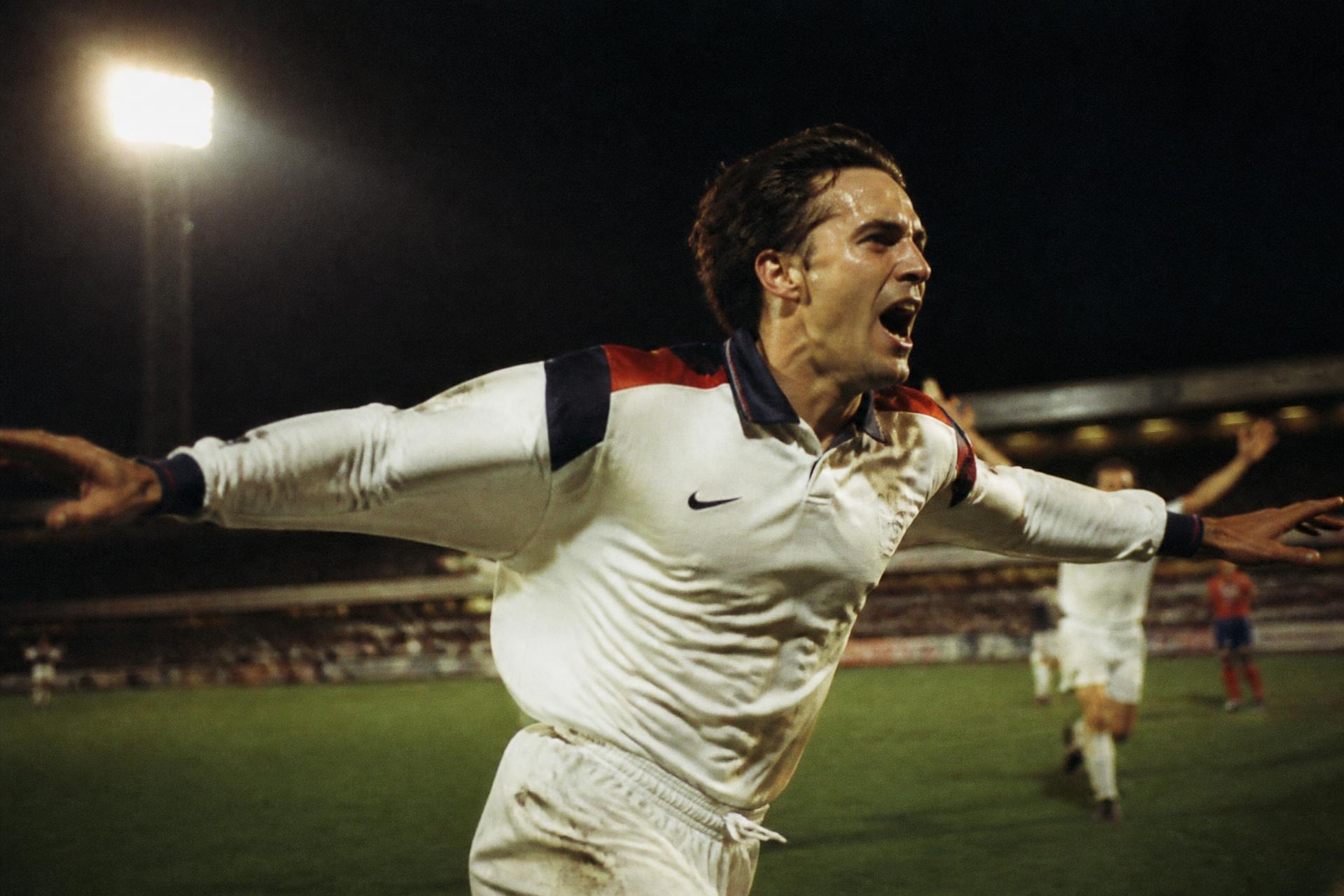 Footballer celebrating under stadium floodlights